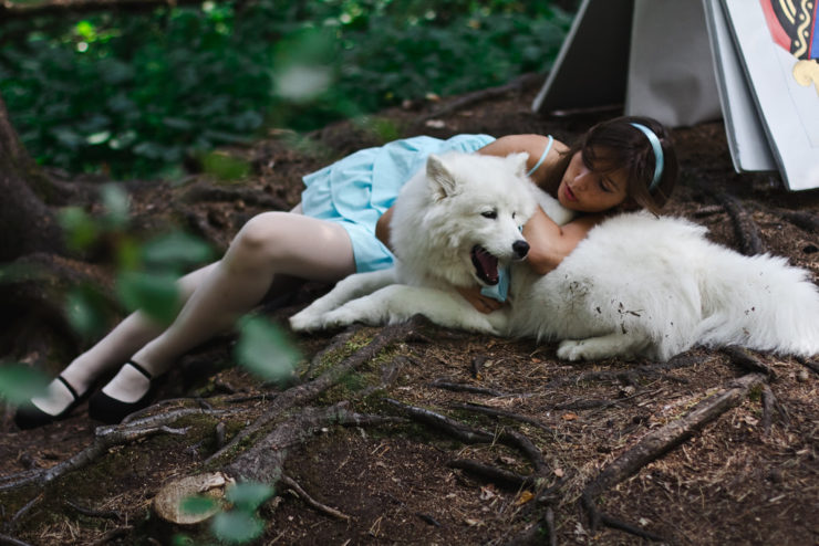 A woman with her Samoyed girl dog lying in the wood